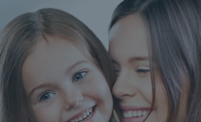 Mother and daughter smiling with pretty teeth for a picture.
