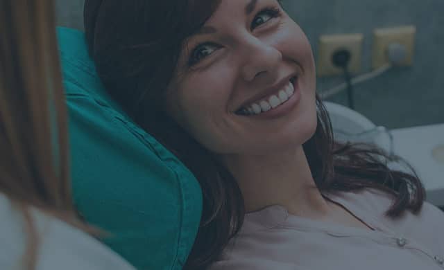 Woman in a patient chair smiling back at the doctor.