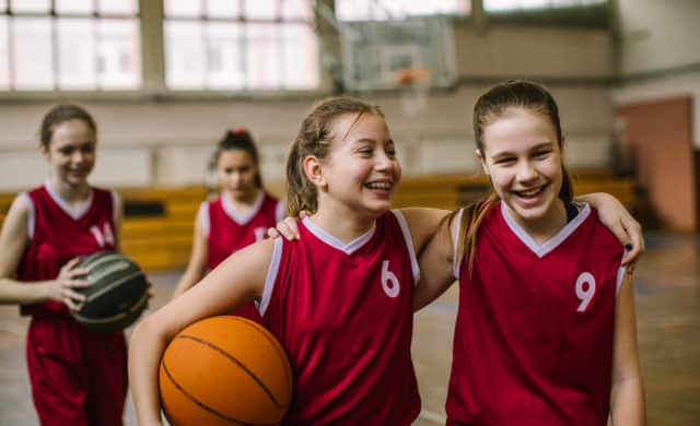 Teenaged girls smiling at their school basketball game.