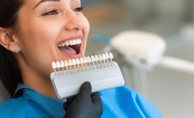 woman patient sitting in a chair looking at shade of dental implants