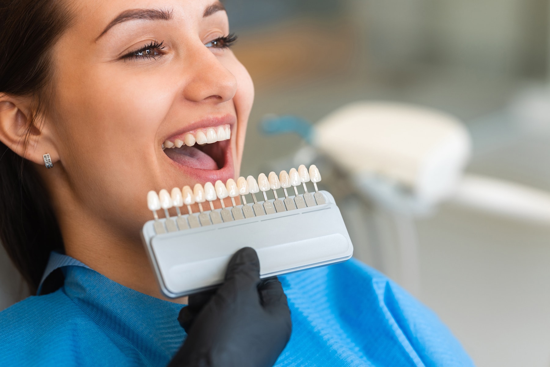 woman patient sitting in a chair looking at shade of dental implants