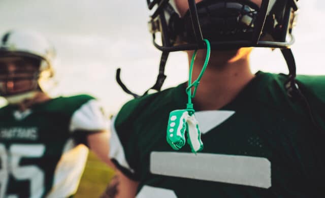 young football player with helmet and mouthguard - header for National Facial Protection Month Blog