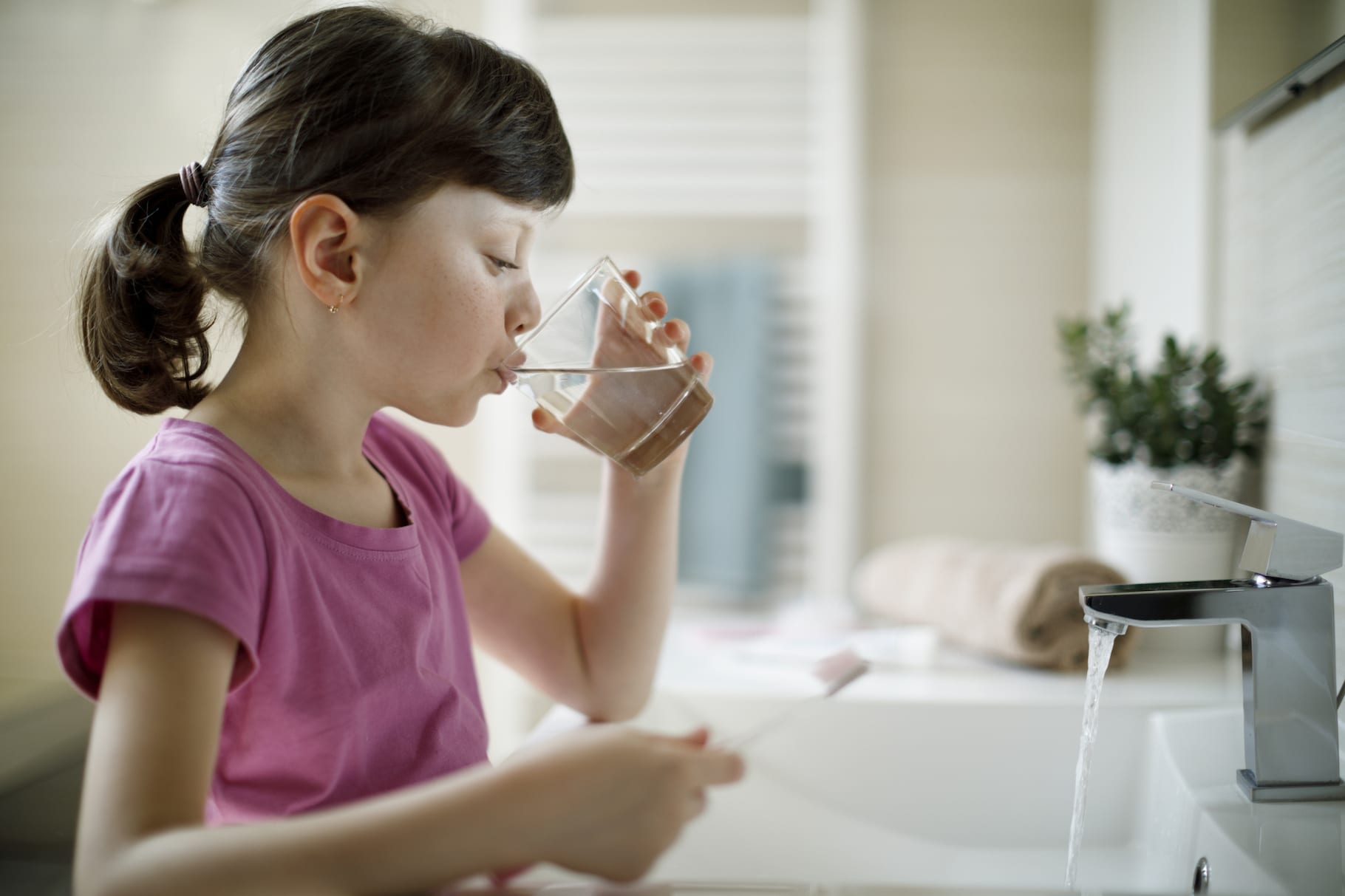 Young girl rinsing mouth in the bathroom with water after brushing teeth