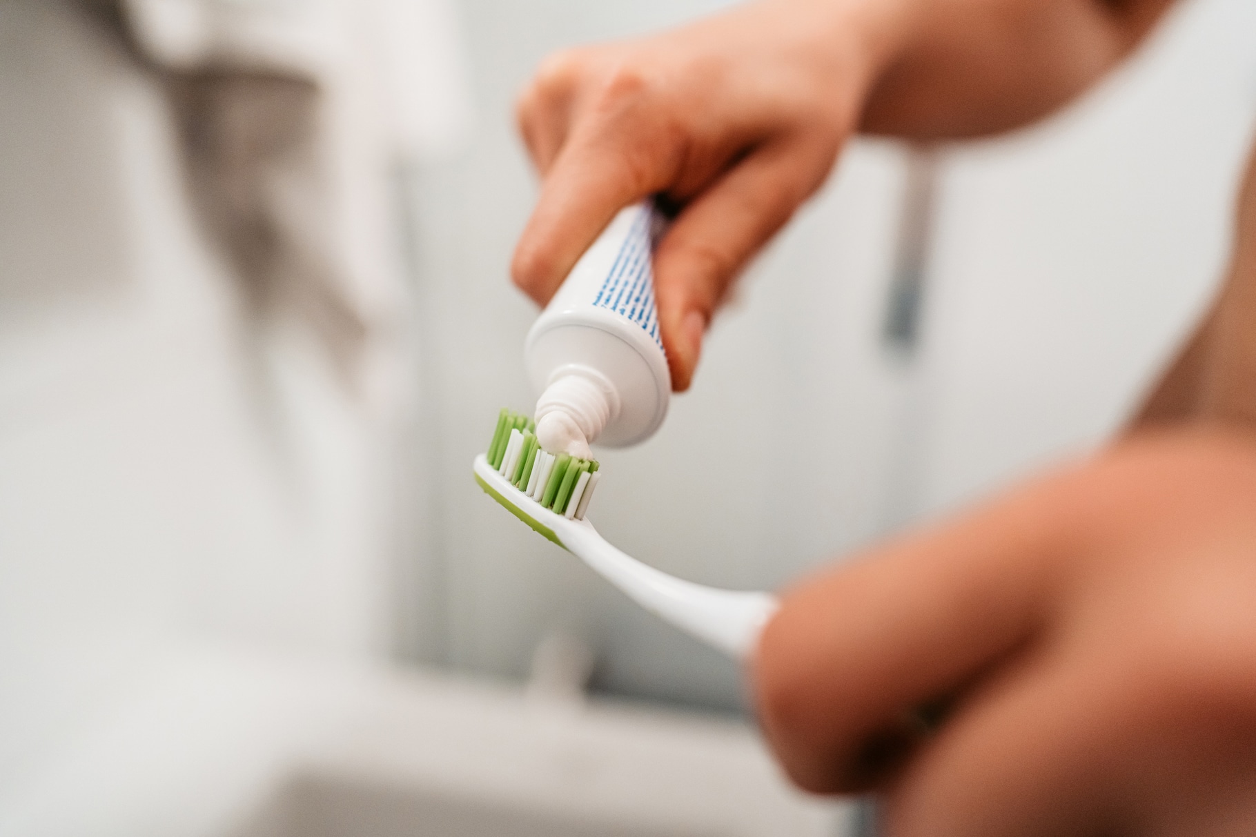 how often should you change your toothbrush blog image of adult adding toothpaste to toothbrush